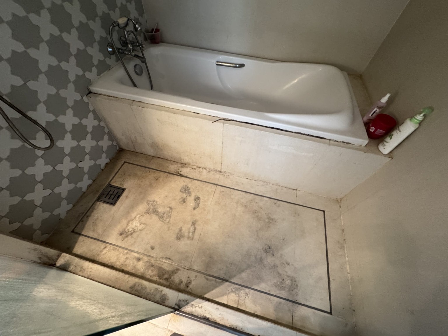 Bathtub and shower area showing discoloration and aged finishes