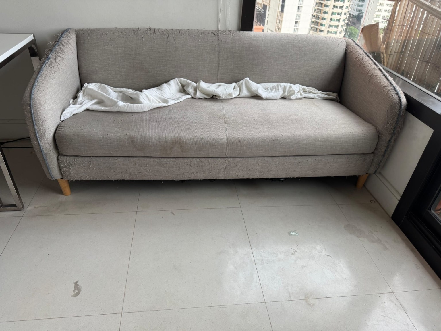 Visible fraying and unraveling along the lower sofa upholstery